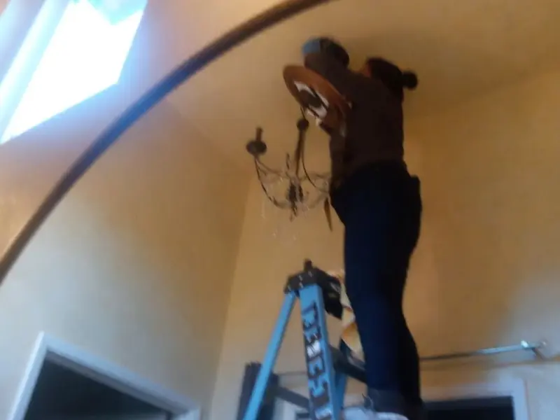 Electrician installing a chandelier in a Winterport residence